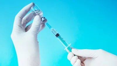 Врач держит шприц и медикамент в руках